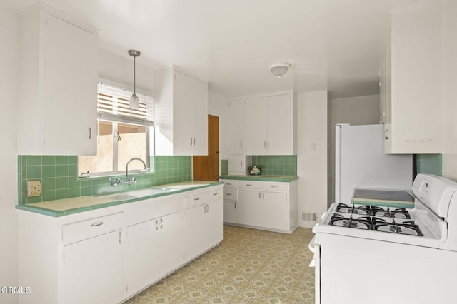 kitchen featuring tile countertops, tasteful backsplash, white cabinetry, a sink, and white appliances