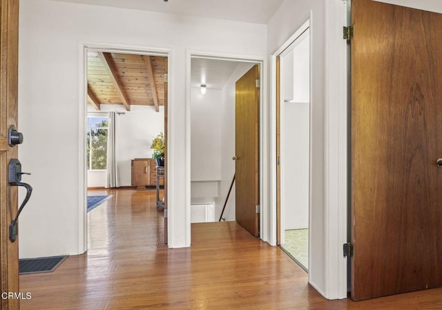 hall with beam ceiling, visible vents, an upstairs landing, wood finished floors, and wooden ceiling