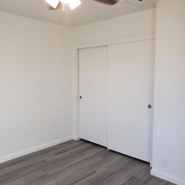 unfurnished bedroom featuring a closet, dark wood-type flooring, and ceiling fan