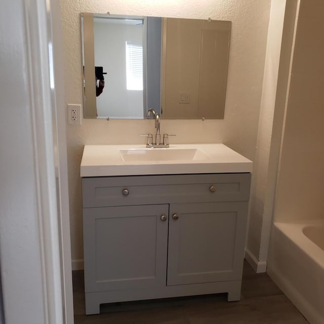 bathroom with a washtub, vanity, and wood-type flooring