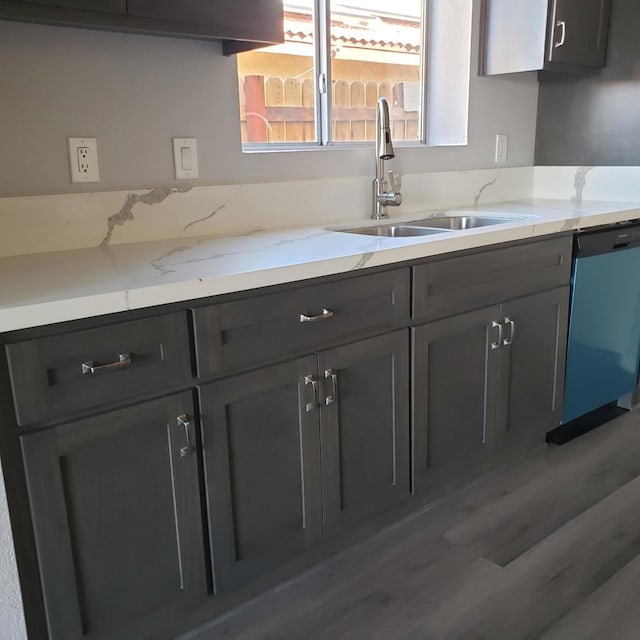 kitchen featuring hardwood / wood-style flooring, dishwasher, light stone counters, and sink