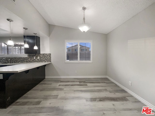 unfurnished dining area featuring light wood-type flooring, lofted ceiling, and sink