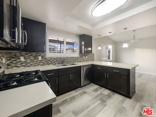 kitchen featuring sink, hanging light fixtures, stainless steel appliances, tasteful backsplash, and kitchen peninsula