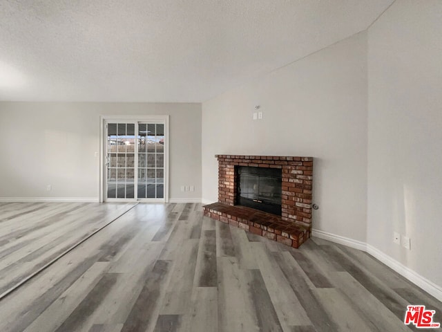 unfurnished living room with a fireplace, wood-type flooring, and a textured ceiling