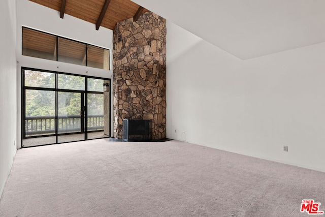 unfurnished living room with carpet, a stone fireplace, wooden ceiling, and high vaulted ceiling