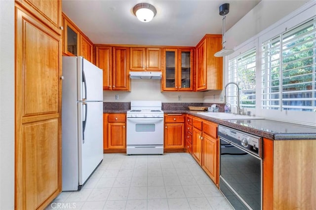 kitchen with dark stone countertops, sink, white appliances, and hanging light fixtures