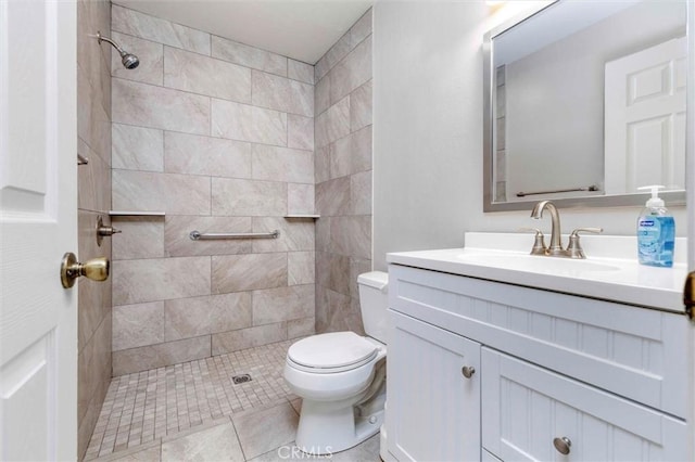 bathroom with a tile shower, vanity, toilet, and tile patterned floors