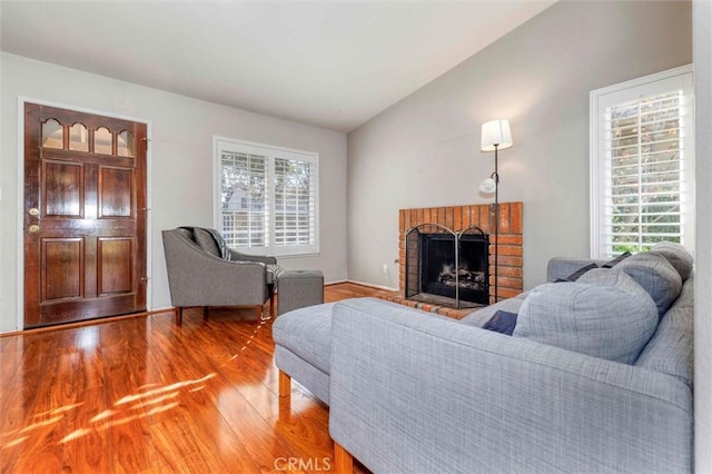 living room featuring hardwood / wood-style flooring, lofted ceiling, a wealth of natural light, and a brick fireplace