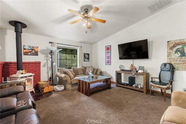 carpeted living area with lofted ceiling, a wood stove, a ceiling fan, and visible vents