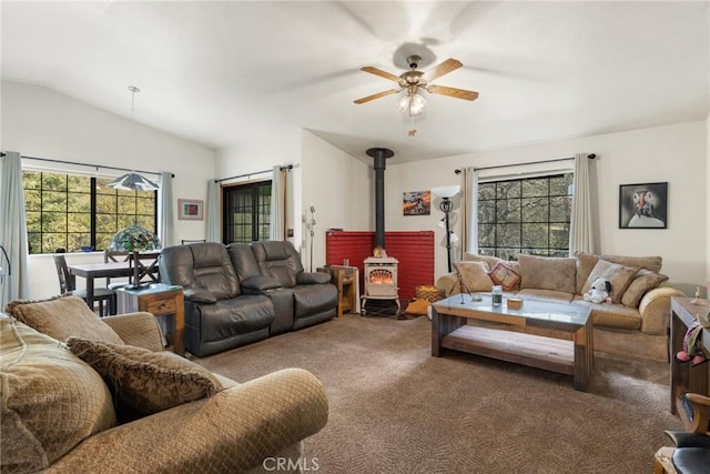 carpeted living room featuring lofted ceiling, a wood stove, and a ceiling fan