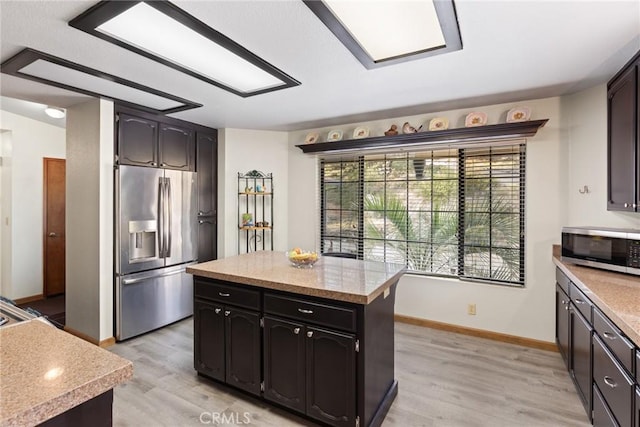 kitchen featuring a center island, stainless steel appliances, light wood-style floors, light countertops, and baseboards