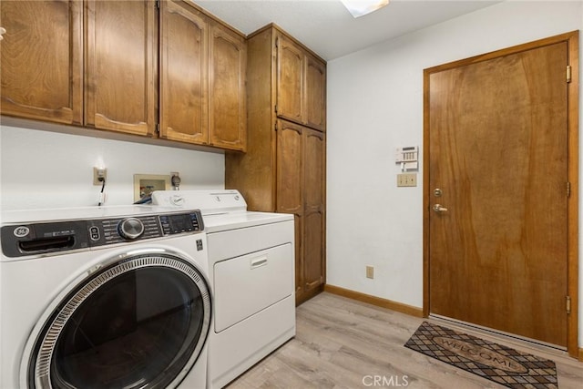 clothes washing area featuring washer and dryer, cabinet space, light wood-style floors, and baseboards