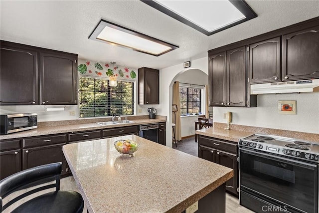 kitchen featuring black appliances, under cabinet range hood, a sink, arched walkways, and dark brown cabinets