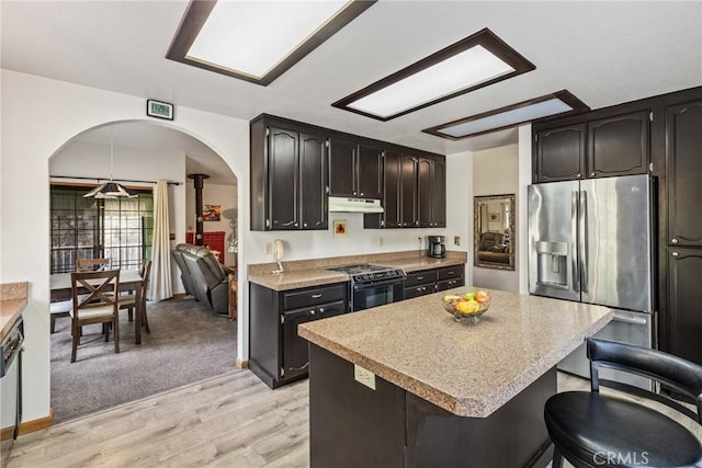 kitchen featuring light countertops, electric range, stainless steel fridge, and under cabinet range hood