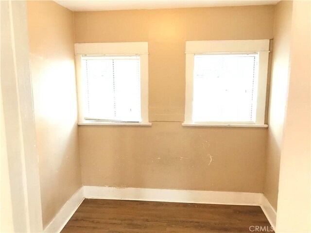 unfurnished room featuring plenty of natural light and dark wood-type flooring