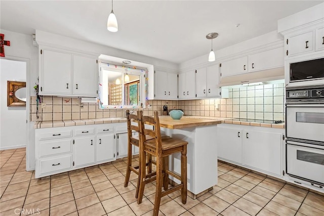 kitchen with decorative light fixtures, white cabinetry, and black electric stovetop