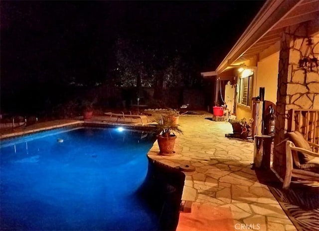 pool at twilight featuring a patio