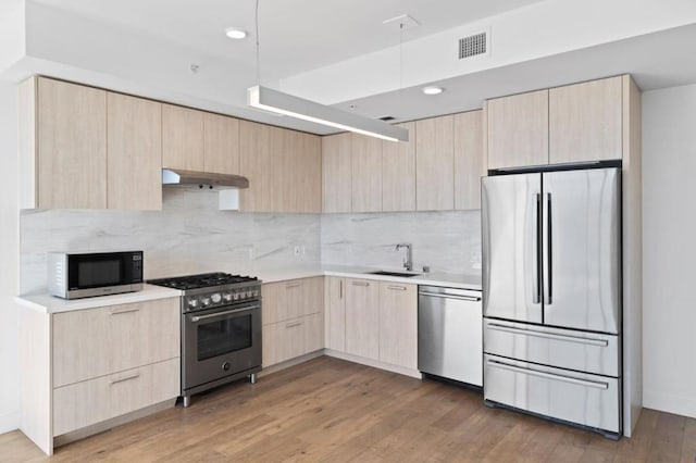 kitchen with hardwood / wood-style floors, light brown cabinetry, stainless steel appliances, and sink