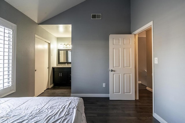 bedroom featuring dark hardwood / wood-style floors, vaulted ceiling, and ensuite bath