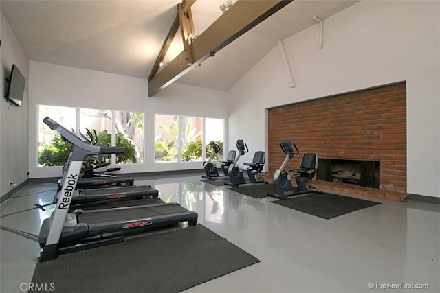 exercise room featuring a fireplace and high vaulted ceiling