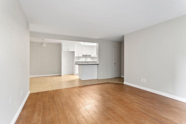 unfurnished living room featuring ceiling fan, sink, and light hardwood / wood-style flooring