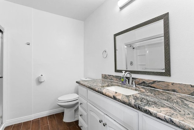 bathroom with a shower, hardwood / wood-style floors, vanity, and toilet