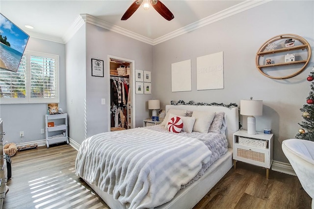 bedroom featuring dark hardwood / wood-style flooring, a spacious closet, ceiling fan, crown molding, and a closet