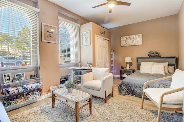 bedroom with a closet, baseboards, light wood-style floors, and ceiling fan