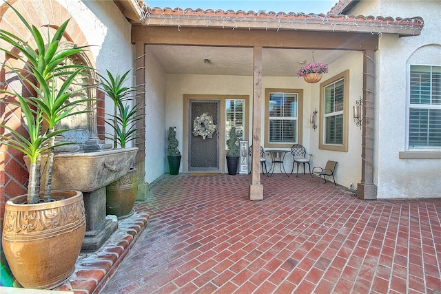 entrance to property with a tiled roof and stucco siding