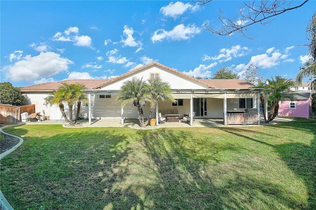 rear view of property featuring a yard, a patio area, and stucco siding