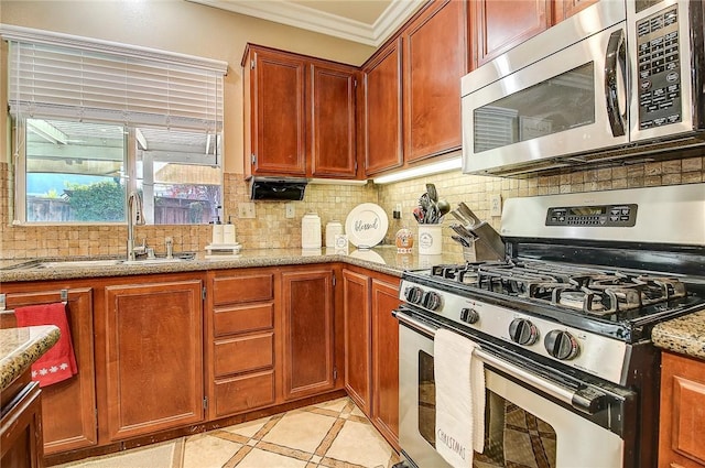 kitchen featuring light stone countertops, ornamental molding, decorative backsplash, a sink, and appliances with stainless steel finishes