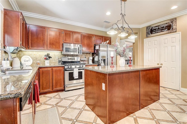 kitchen featuring appliances with stainless steel finishes, a center island, sink, and decorative light fixtures