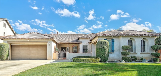 mediterranean / spanish-style house featuring a front yard, stucco siding, driveway, an attached garage, and a gate