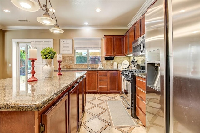 kitchen with a kitchen island, appliances with stainless steel finishes, pendant lighting, tasteful backsplash, and light stone counters