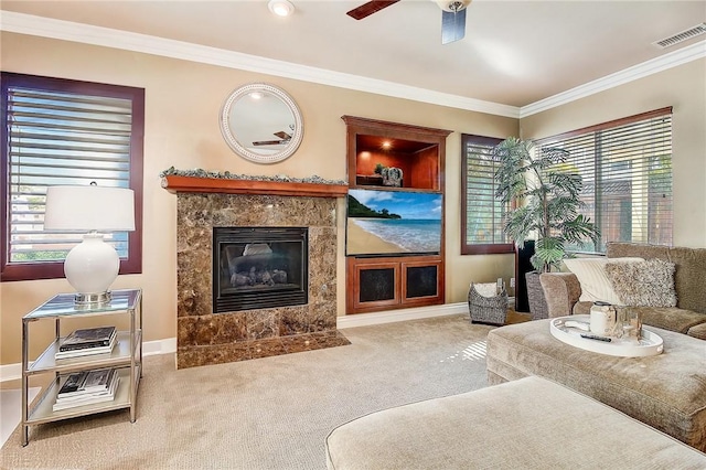 living room with ceiling fan, a fireplace, ornamental molding, and carpet flooring