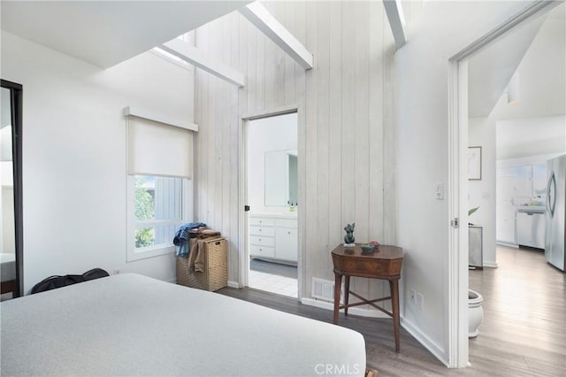 253 Fairview St, Laguna Beach, CA 92651 - bedroom featuring connected bathroom, freestanding refrigerator, wooden walls, wood finished floors, and visible vents