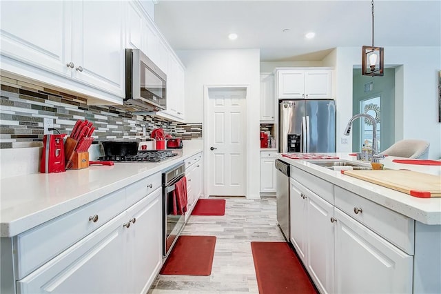 kitchen with light wood-type flooring, stainless steel appliances, sink, a center island with sink, and white cabinets