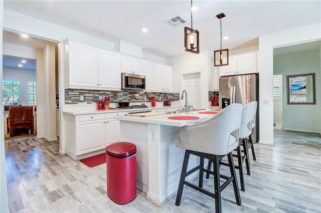 kitchen with light hardwood / wood-style flooring, white cabinetry, stainless steel appliances, and an island with sink