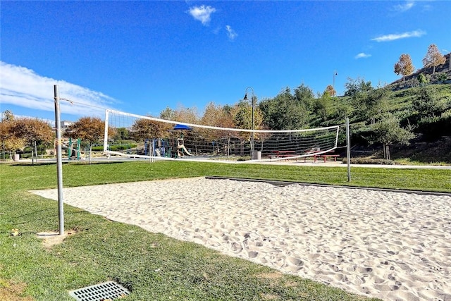 view of home's community featuring volleyball court, a playground, and a lawn