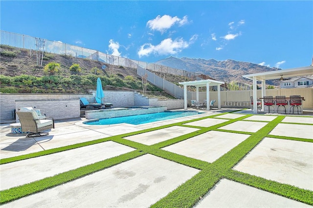 view of swimming pool featuring a mountain view, ceiling fan, and a patio