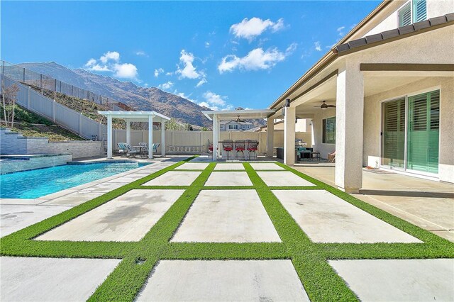 view of pool with a mountain view, ceiling fan, a patio area, and a pergola