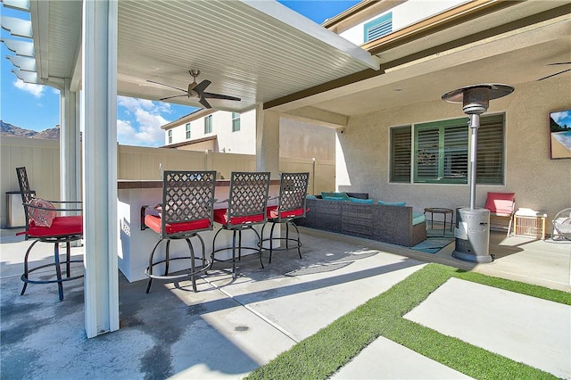 view of patio with outdoor lounge area, ceiling fan, and a bar