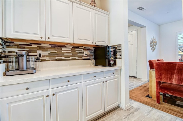 kitchen featuring decorative backsplash, white cabinets, and light hardwood / wood-style floors