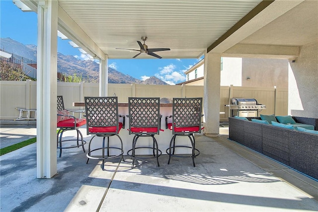 view of patio / terrace with outdoor lounge area, ceiling fan, a bar, grilling area, and a mountain view