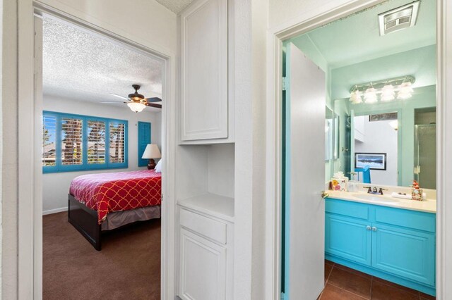 carpeted bedroom with ceiling fan, sink, and a textured ceiling