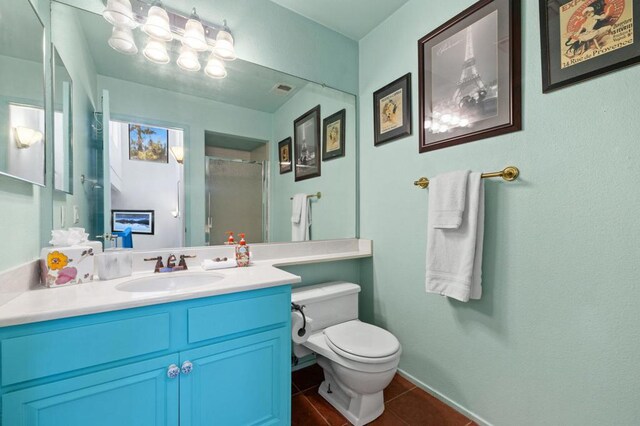 bathroom with tile patterned flooring, vanity, toilet, and a shower with door