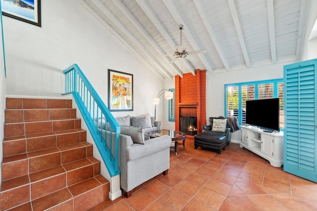 tiled living room with ceiling fan, beamed ceiling, high vaulted ceiling, and a brick fireplace