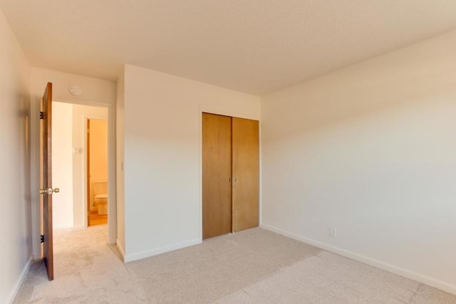 unfurnished bedroom with light colored carpet and a closet