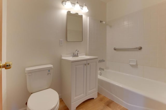 full bathroom with hardwood / wood-style flooring, vanity, tiled shower / bath, and toilet