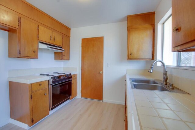 kitchen featuring range with electric cooktop, sink, tile counters, and light hardwood / wood-style floors